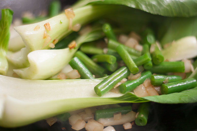 Stir fried pak choi and beans in a wok