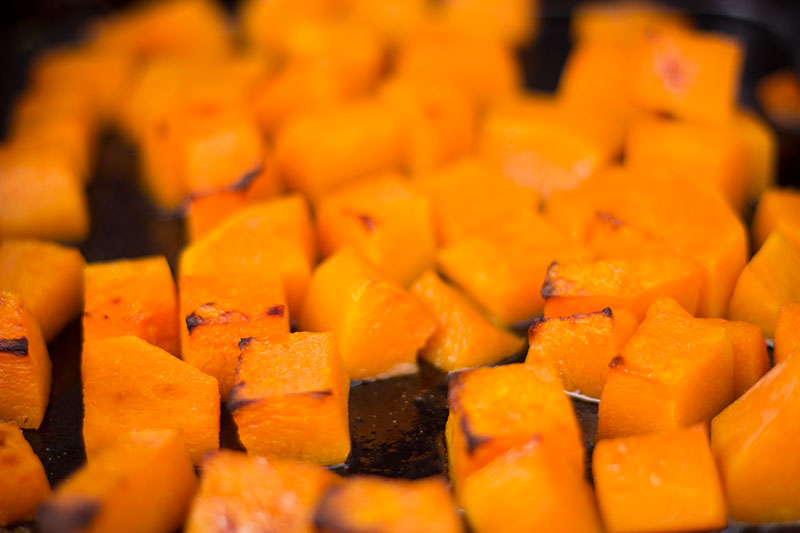 A tray full of roasted butternut squash just browning on the edges