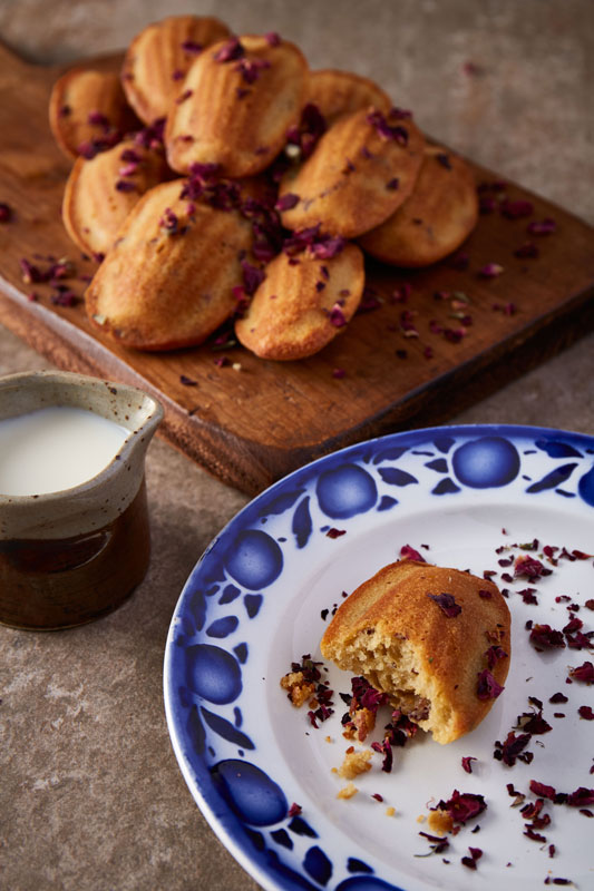 Whimsical spelt madeleines flavoured with fragrant rosewater and decorated with delicate edible rose petals are a delicious afternoon tea time treat as well as being made with no refined sugar, so feature high up on the healthy bake stakes!